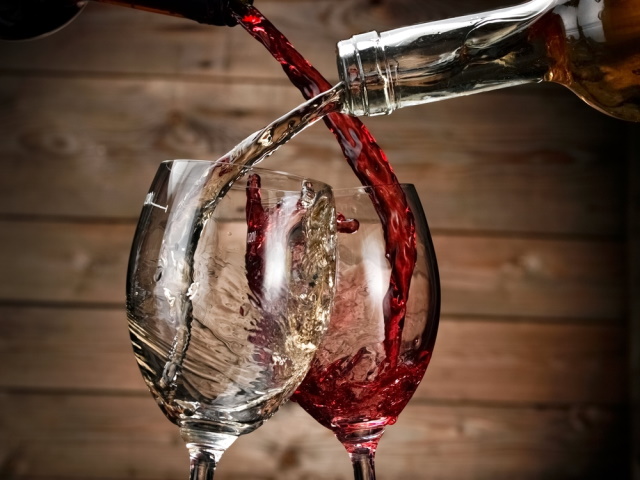 White and red wine being poured into two glasses